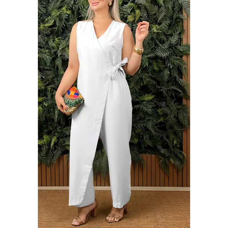 Woman wearing a white jumpsuit with a colorful clutch in front of greenery