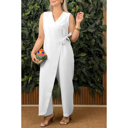 Woman wearing a white jumpsuit with a colorful clutch in front of greenery